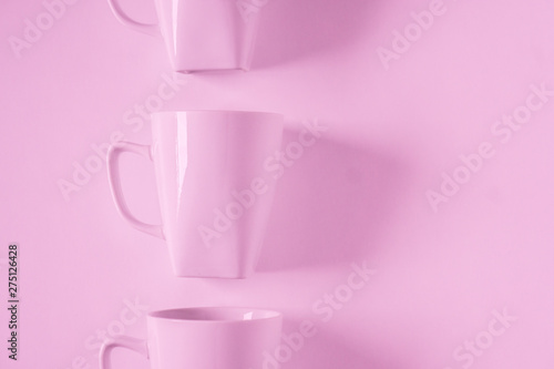 Pink coffee mugs on pink background in a vertical row with empty copyspace