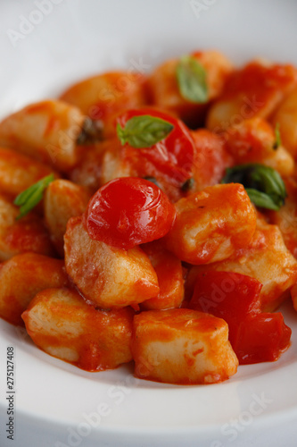 close up of Gnocchi with cherry tomatoes and basil isolated on a white plate and white background