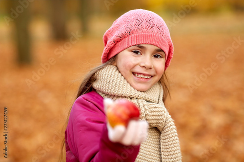 childhood  season and people concept - happy girl with apple at autumn park