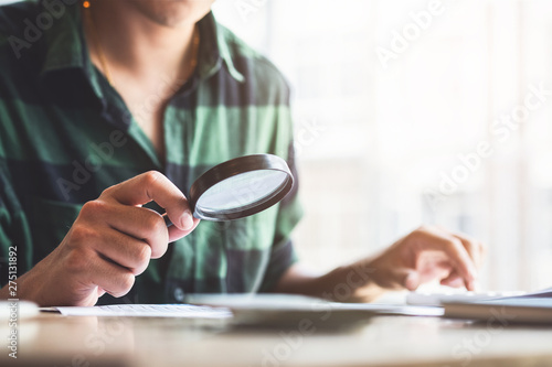 Man looking through a magnifying glass to documents. Business assessment and audit. Magnifying glass on a financial report. Close-up Of person Checking Bills With Magnifying Glass.Concept of search