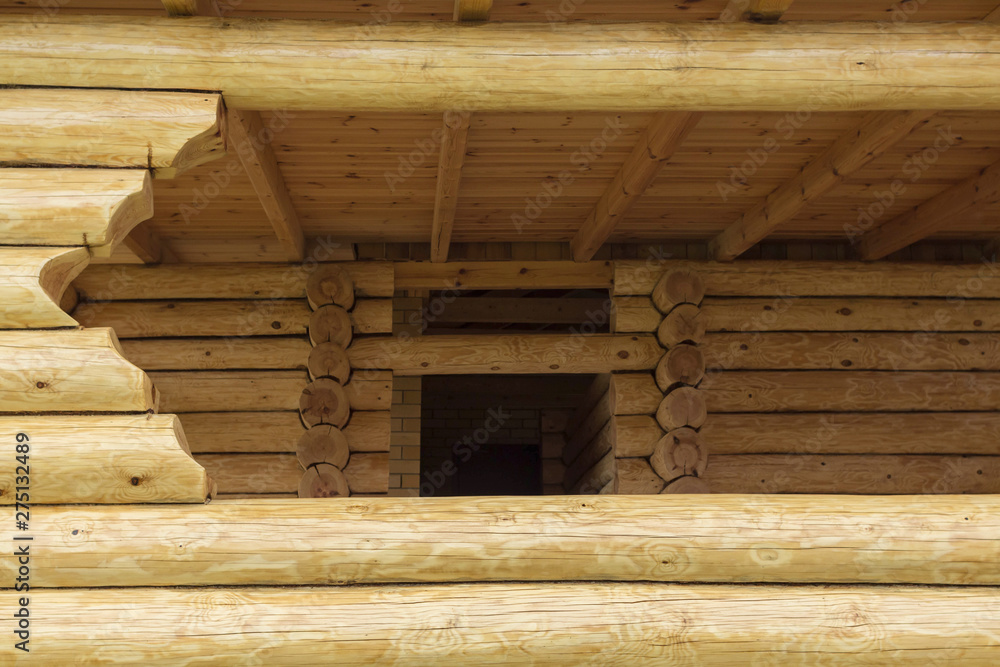 Gazebo made of logs. Window in wooden terrace. Elements of wooden construction.