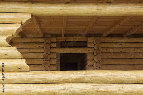 Gazebo made of logs. Window in wooden terrace. Elements of wooden construction.