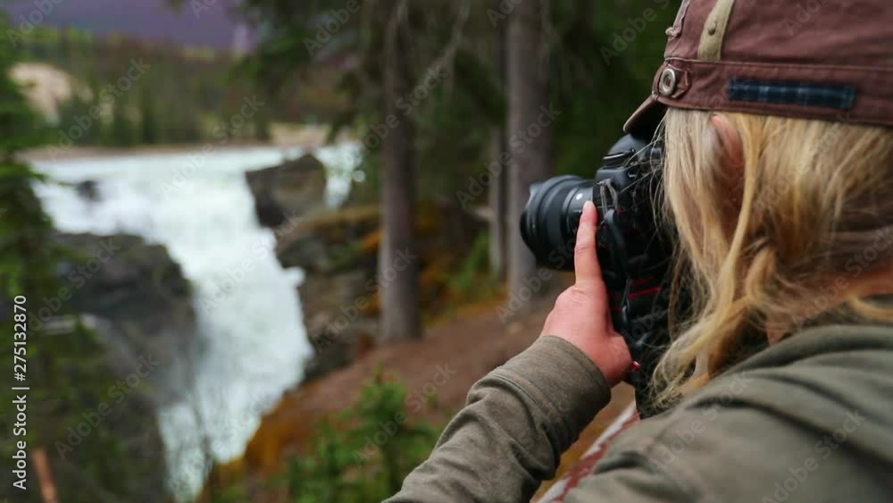 Looking over shoulder of blonde, female photographer shooting a waterfall in Jasper National Park Looking over shoulder of blonde, female photographer shooting a waterfall in Jasper National Park