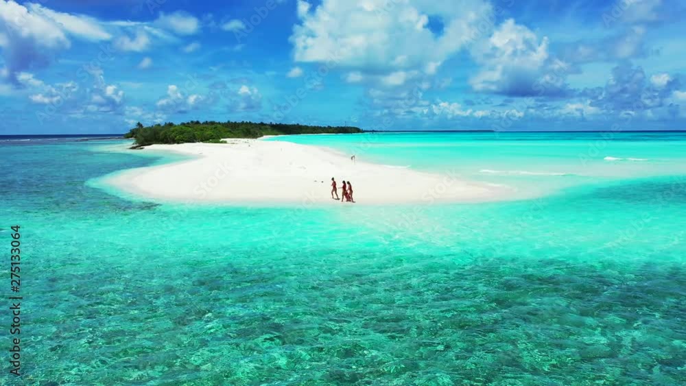 Aerial view of a sandy island with three young women in red bathing cloths walking on. In the turquoise Maldivian Sea under a dramatic blue Sky. Dolly out with a truck left. Aerial view of a sandy island with three young women in red bathing cloths walking on. In the turquoise Maldivian Sea under a dramatic blue Sky. Dolly out with a truck left.