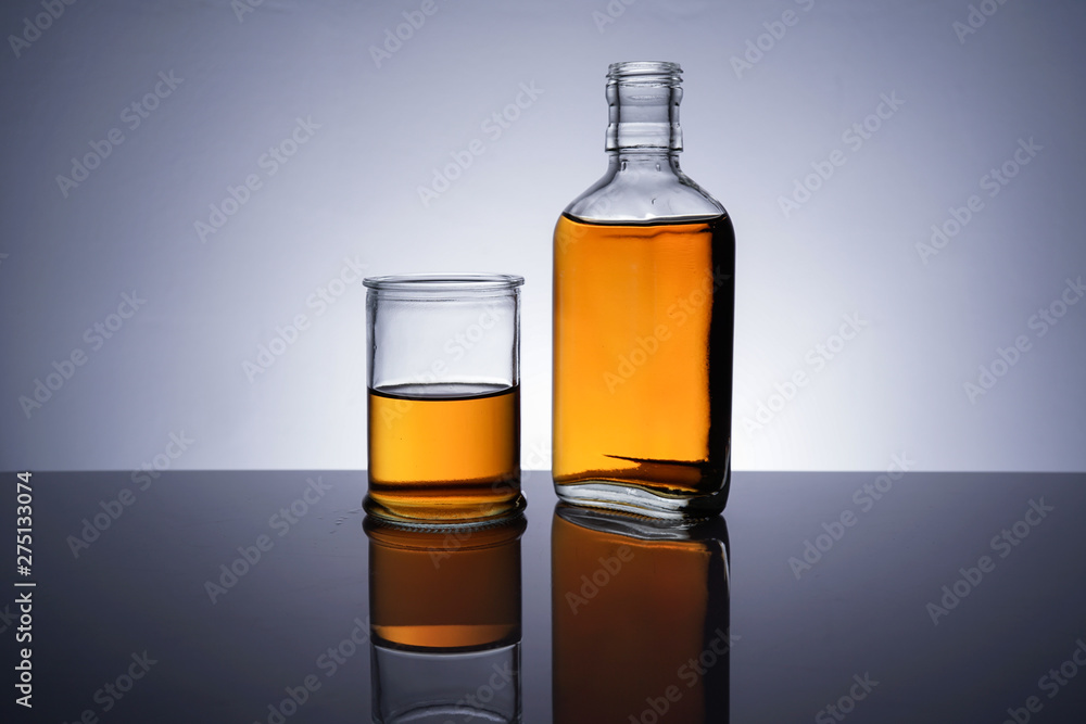 A backlit of a glass bottle and jar with golden liquid A backlit of a glass bottle and jar with golden liquid