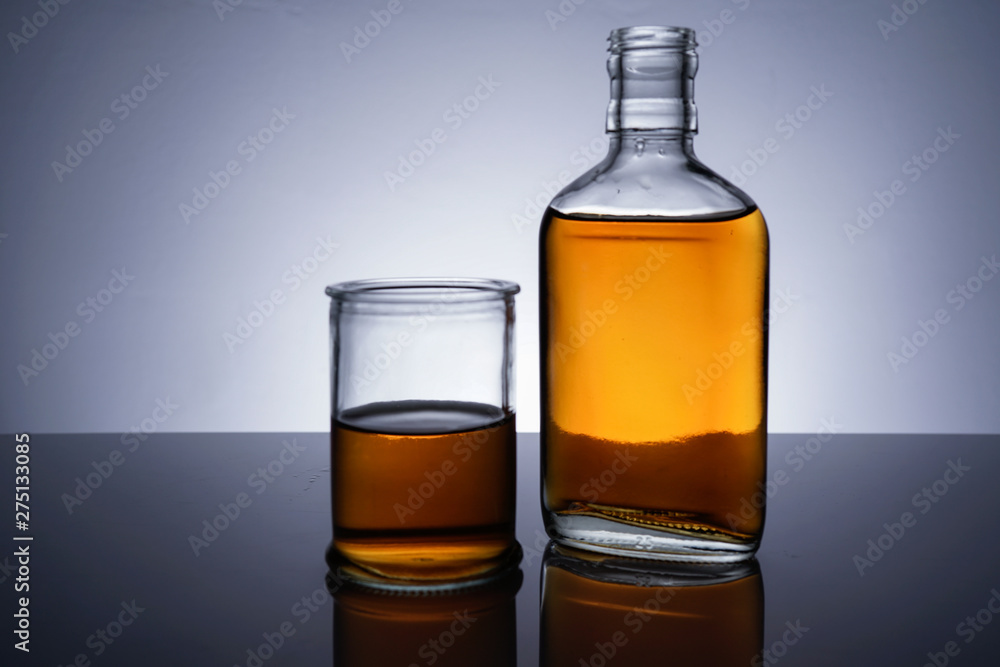 A backlit of a glass bottle and jar with golden liquid A backlit of a glass bottle and jar with golden liquid