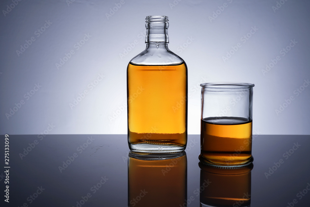 A backlit of a glass bottle and jar with golden liquid A backlit of a glass bottle and jar with golden liquid