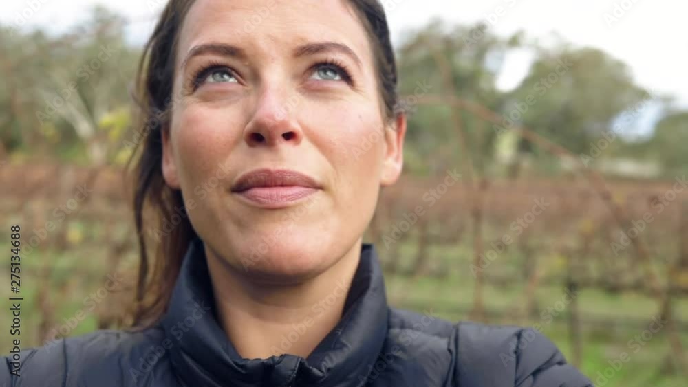 A young woman stands in a winter vineyard, looks up to the sky and smiles. Slow motion A young woman stands in a winter vineyard, looks up to the sky and smiles. Slow motion