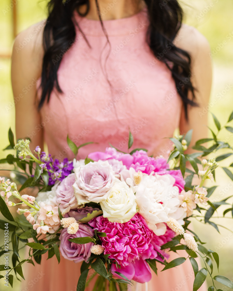 Beautiful wedding bouquet in bride's hands. Modern bouquet of different flowers.