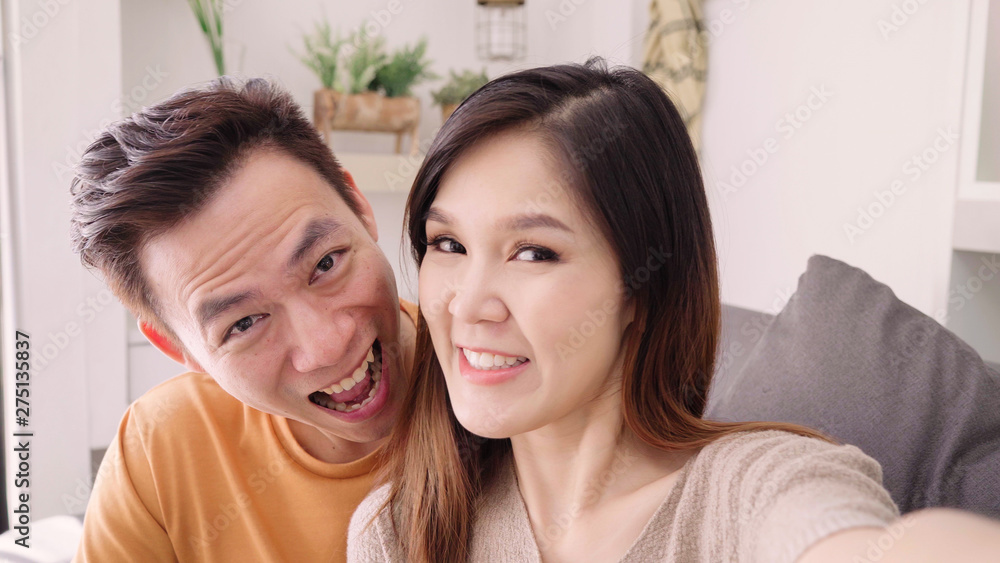 Asian couple using smartphone VIDEO Call with friend in living room at home, sweet couple enjoy love moment while lying on the sofa when relaxed at home. Lifestyle couple relax at home concept. Asian couple using smartphone VIDEO Call with friend in living room at home, sweet couple enjoy love moment while lying on the sofa when relaxed at home. Lifestyle couple relax at home concept.