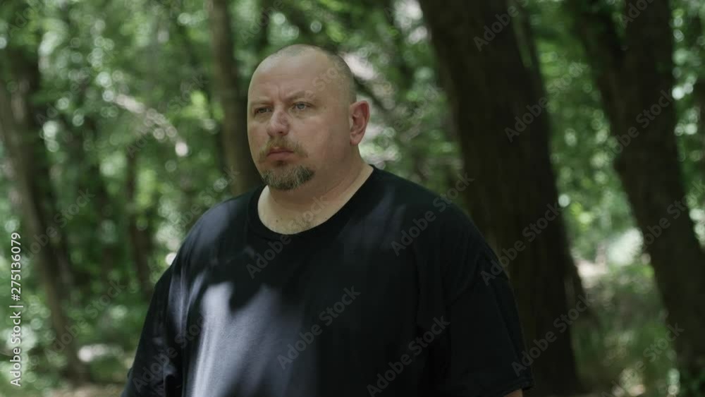 A man walking through forest trees. Tree shadows fall on him and sunlight shines through. Slowmotion clip. A man walking through forest trees. Tree shadows fall on him and sunlight shines through. Slowmotion clip.