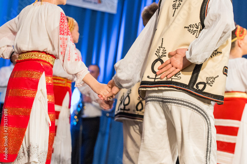 Young Romanian dancer hold hand on his back while perform a folk dance in traditional folkloric costume. Folklore of Romania