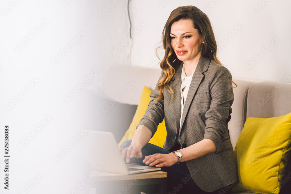 Concentrated at work. Confident young adult middle-aged woman in smart casual clothes, working on a laptop, sitting inside a creative office or cafe. Theme business woman work in free space Concentrated at work. Confident young adult middle-aged woman in smart casual clothes, working on a laptop, sitting inside a creative office or cafe. Theme business woman work in free space