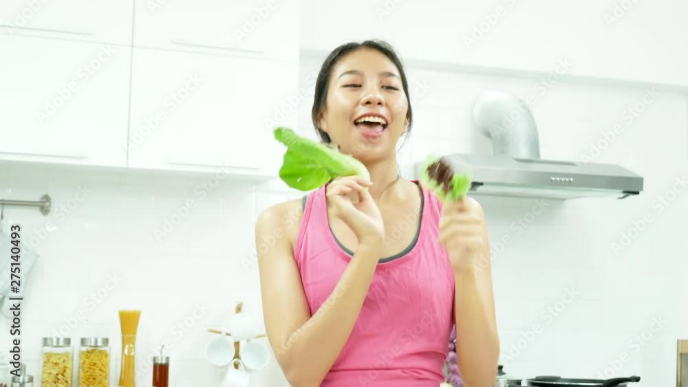 Happiness funny woman vegan dance with fresh vegetable cookery. Mix green salad dancing in kitchen at home cooking. Asian Healthy woman housework lifestyle. Happiness funny woman vegan dance with fresh vegetable cookery. Mix green salad dancing in kitchen at home cooking. Asian Healthy woman housework lifestyle.