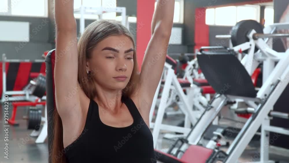 Young fitness woman exercising in the gym with dumbbells sitting on the bench Young fitness woman exercising in the gym with dumbbells sitting on the bench