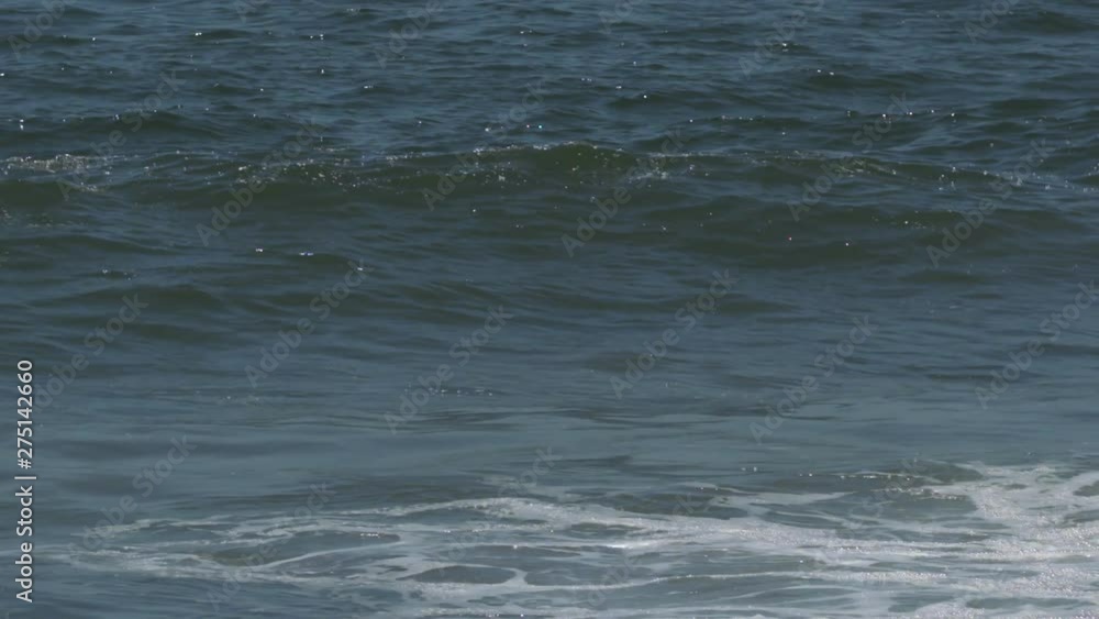 Handheld, medium close up shot of cresting white water waves.