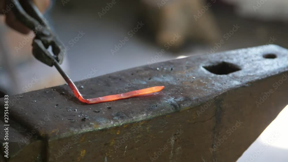 Blacksmith in an apron hitting a red rod in a traditional smithy in Ukraine 