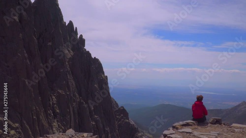 Woman observes the landscape from the rocky mountain