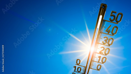 Hot summer or heat wave background, bright sun on blue sky with thermometer photo