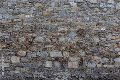 Ancient stone wall. Stone of various shades of gray, brown and yellow. Background.