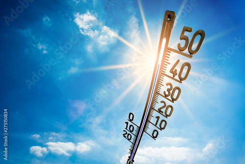 Quadro su tela Hot summer or heat wave background, bright sun on blue sky with thermometer