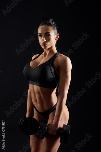 Athletic, sportive, muscular woman posing with dumbbells.