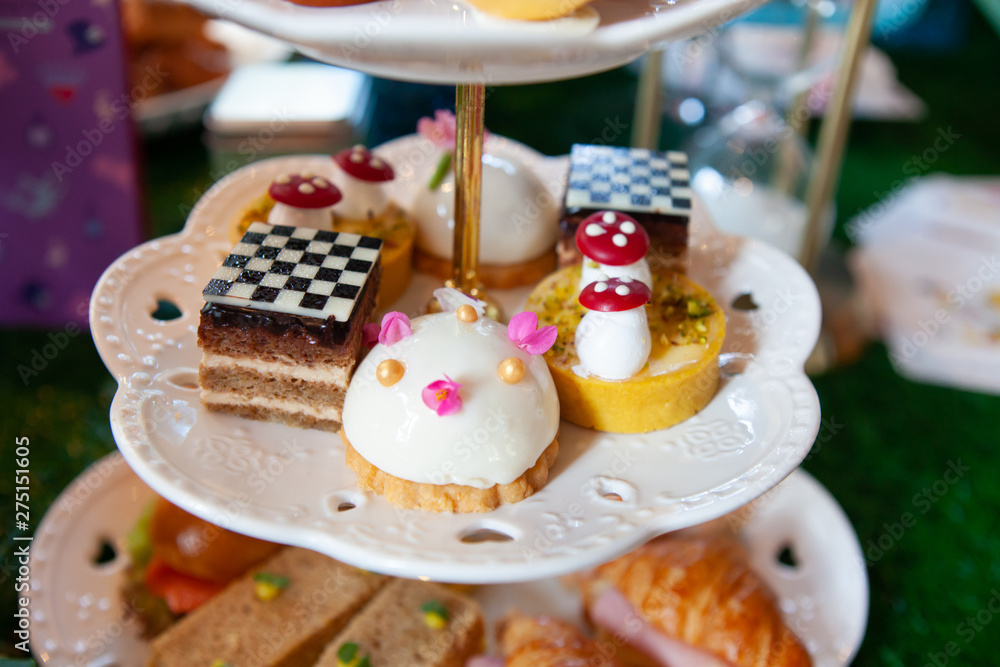 Magical and colorful set of afternoon tea in Alice in Wonderland theme. Tasty and delicious dessert, savories, bakery and pastry. Good for high tea party or Birthday celebration. Natural light.