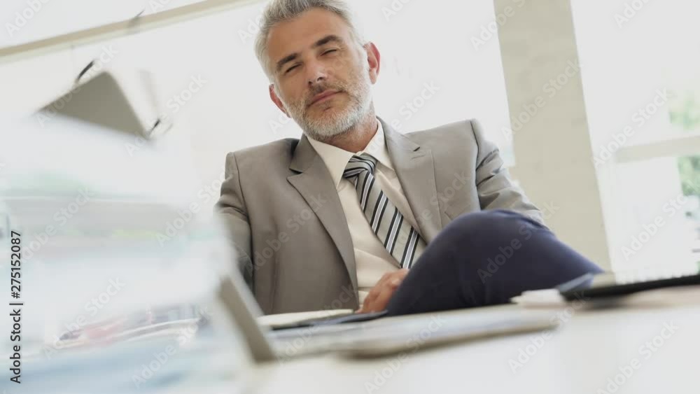Relaxed corporate businessman sitting at desk Relaxed corporate businessman sitting at desk