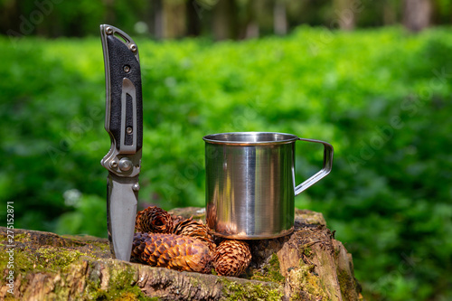 Tourist steel cup and knife in the summer forest