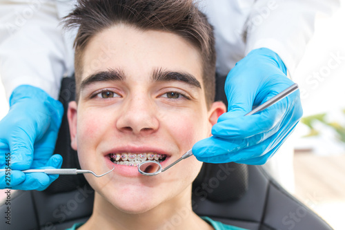 dentist with tools in the young man's mouth with orthodontics photo