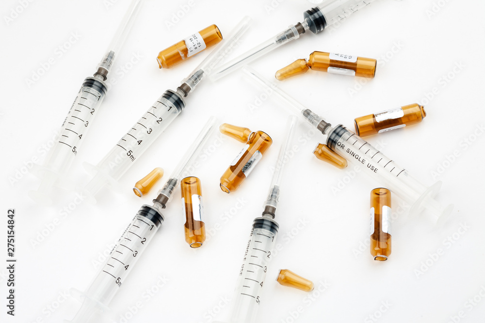 Plastic syringes with used ampoules on a white background, close-up shot, top view