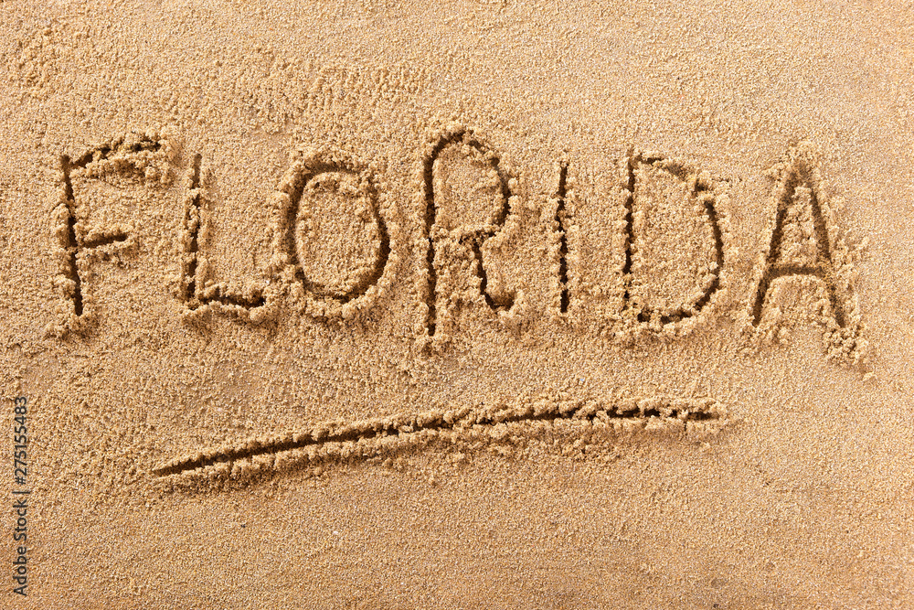 Fototapeta premium Florida word written in sand on a sunny summer beach holiday vacation travel destination sign writing message photo