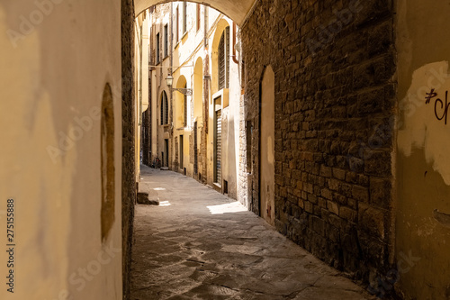 Curved back street with rays of sunshine and shadows