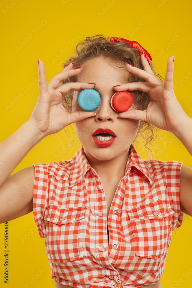 Playful girl holding colorful macarons doing binoculars.