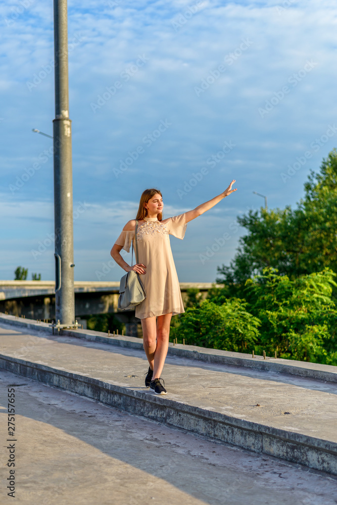 Naklejka premium A young girl is walking along the road, a journey.