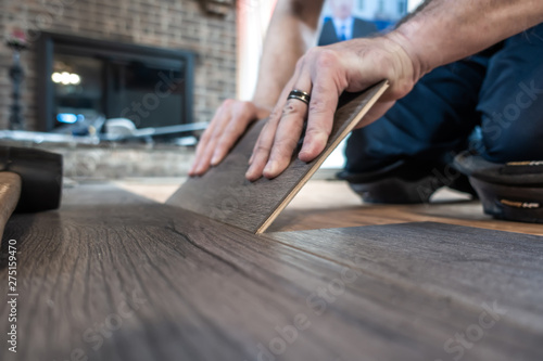 man installing engineered laminate wood floring indoor