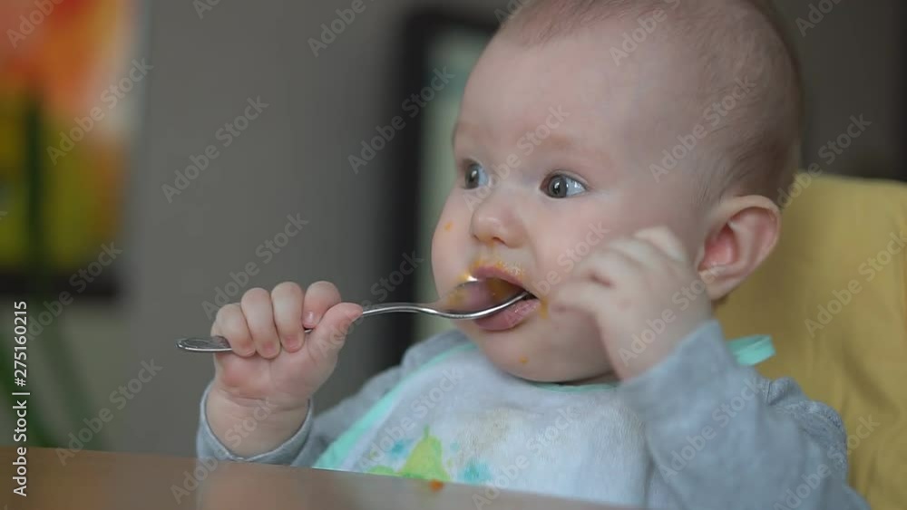Mom gives baby food with a spoon. Mother feeds baby with baby food Mom gives baby food with a spoon. Mother feeds baby with baby food