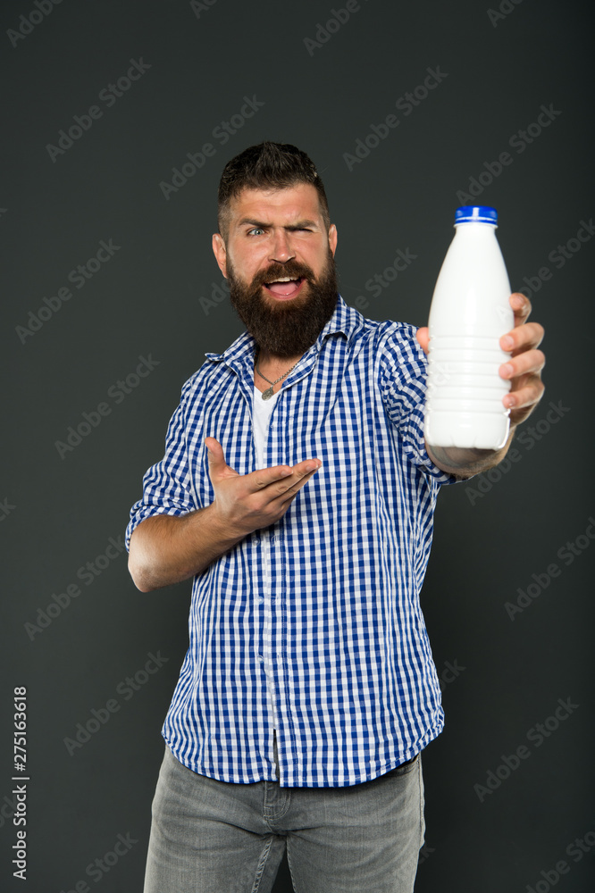 Healthy drinking habits. Happy hipster pointing at bottle for drinking natural milk. Bearded man presenting drinking dairy products. Drinking milk for better digestion Healthy drinking habits. Happy hipster pointing at bottle for drinking natural milk. Bearded man presenting drinking dairy products. Drinking milk for better digestion