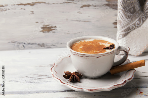 Beautiful cup of traditional indian masala chai tea on with star anise and cinnamon on a shabby wooden texture background