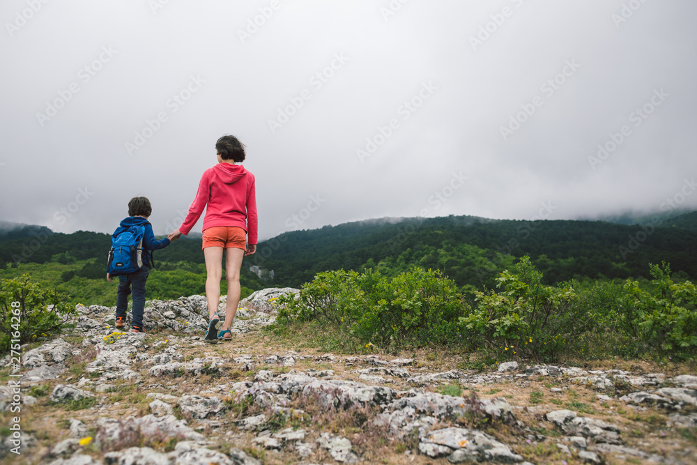 A child with a backpack is walking on a mountain path.