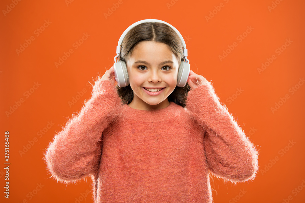 Perfect sound stereo headphones. Girl cute little child wear headphones listen music. Kid listen music orange background. Recommended music based on initial interest. Music produces pleasure - obrazy, fototapety, plakaty 
