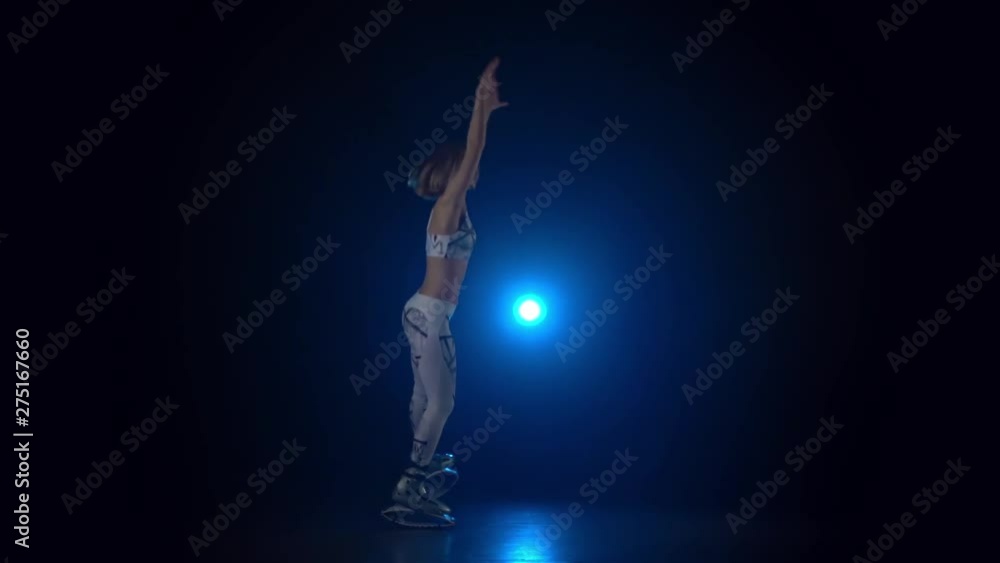 Female dancing in kangoo jumps shoes against blue spotlight. Slow motion Female dancing in kangoo jumps shoes against blue spotlight. Slow motion