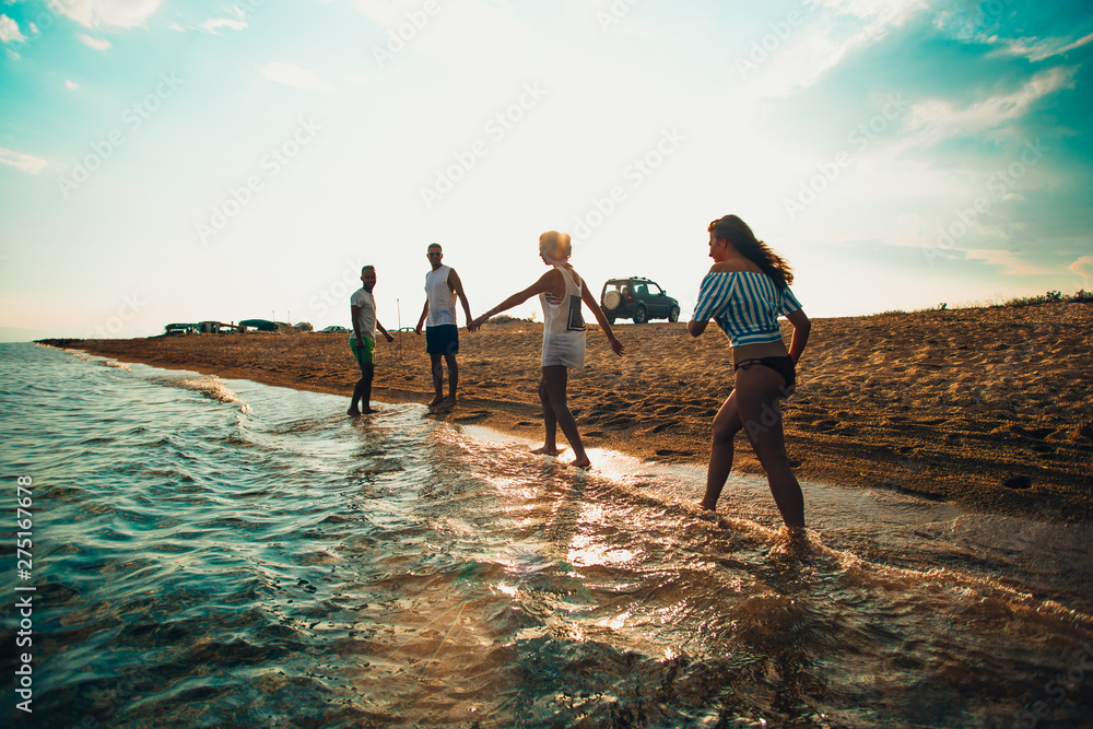 Fototapeta premium Group of happy friends jogging in to water at summer