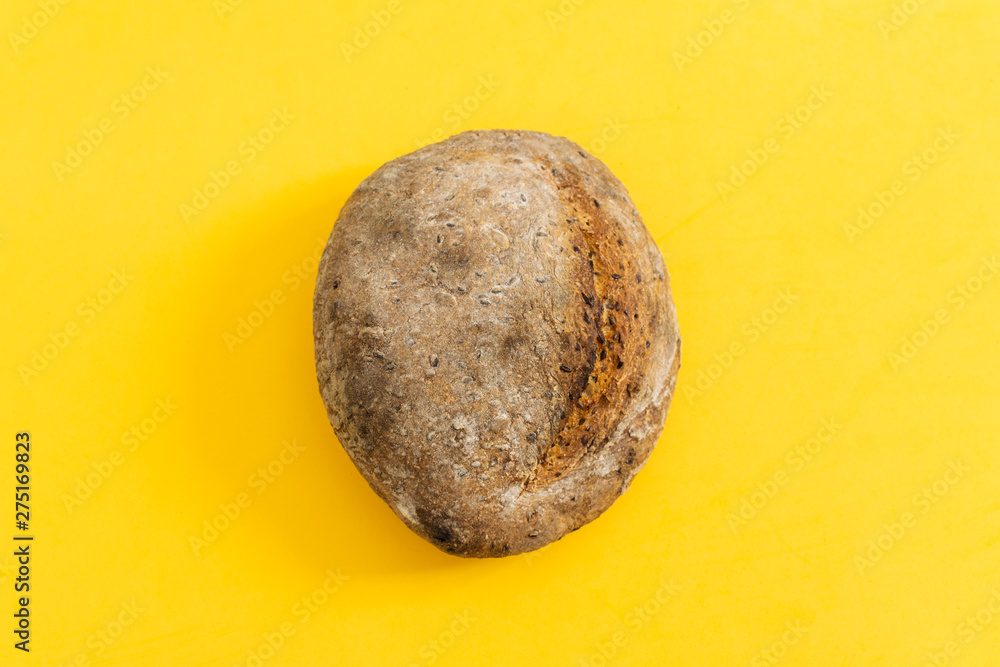 Fototapeta premium Fresh baked organic whole grain rye bread on bright yellow background