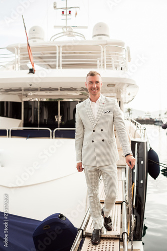 Stylish businessman is standing on his luxury yacht is wearing white fashion costume. Montenegro bay photo