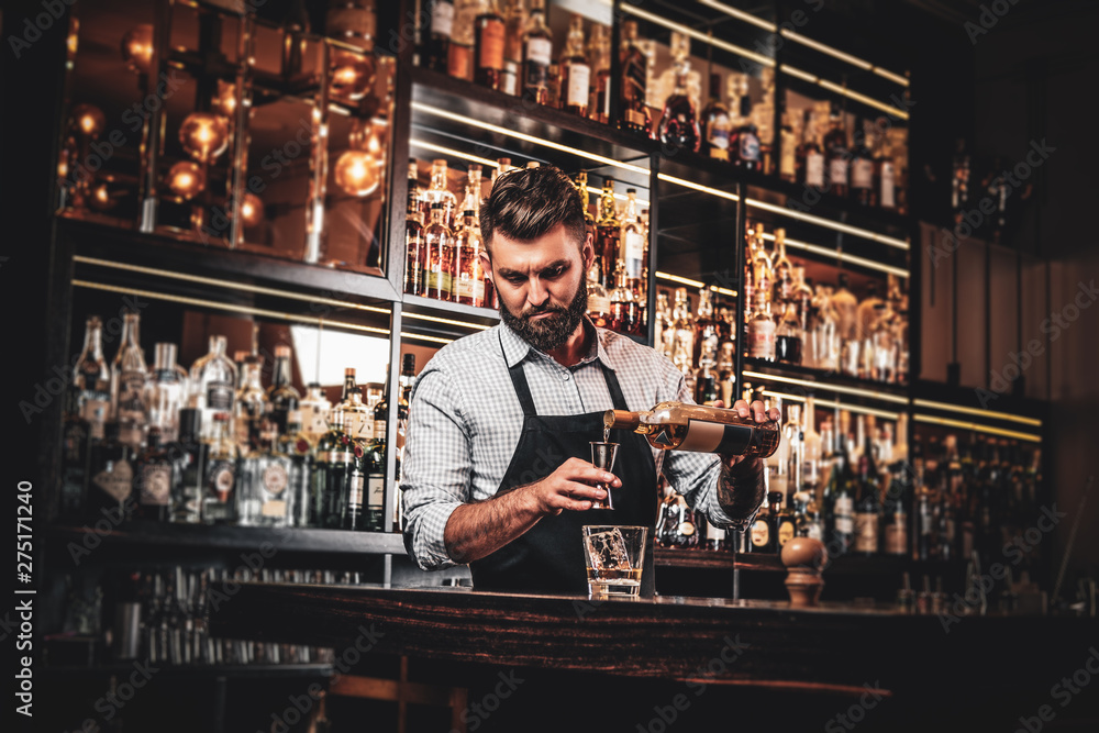 Serious barman is prepairing drinks for customers at posh bar. - obrazy, fototapety, plakaty 