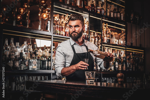 Happy smiling barman is prepairing drinks for customers at posh bar. photo
