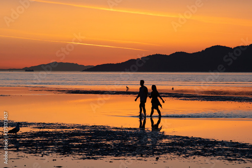 silhouette of a couple on the beach at sunset during a low tide