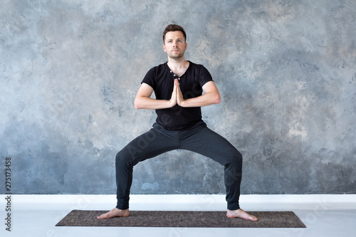 Man working out, yoga, pilates, fitness training, Goddess Pose or rudrasana photo