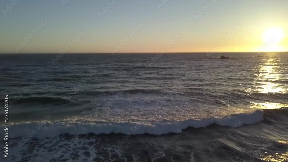Sunset over ocean with waves crashing